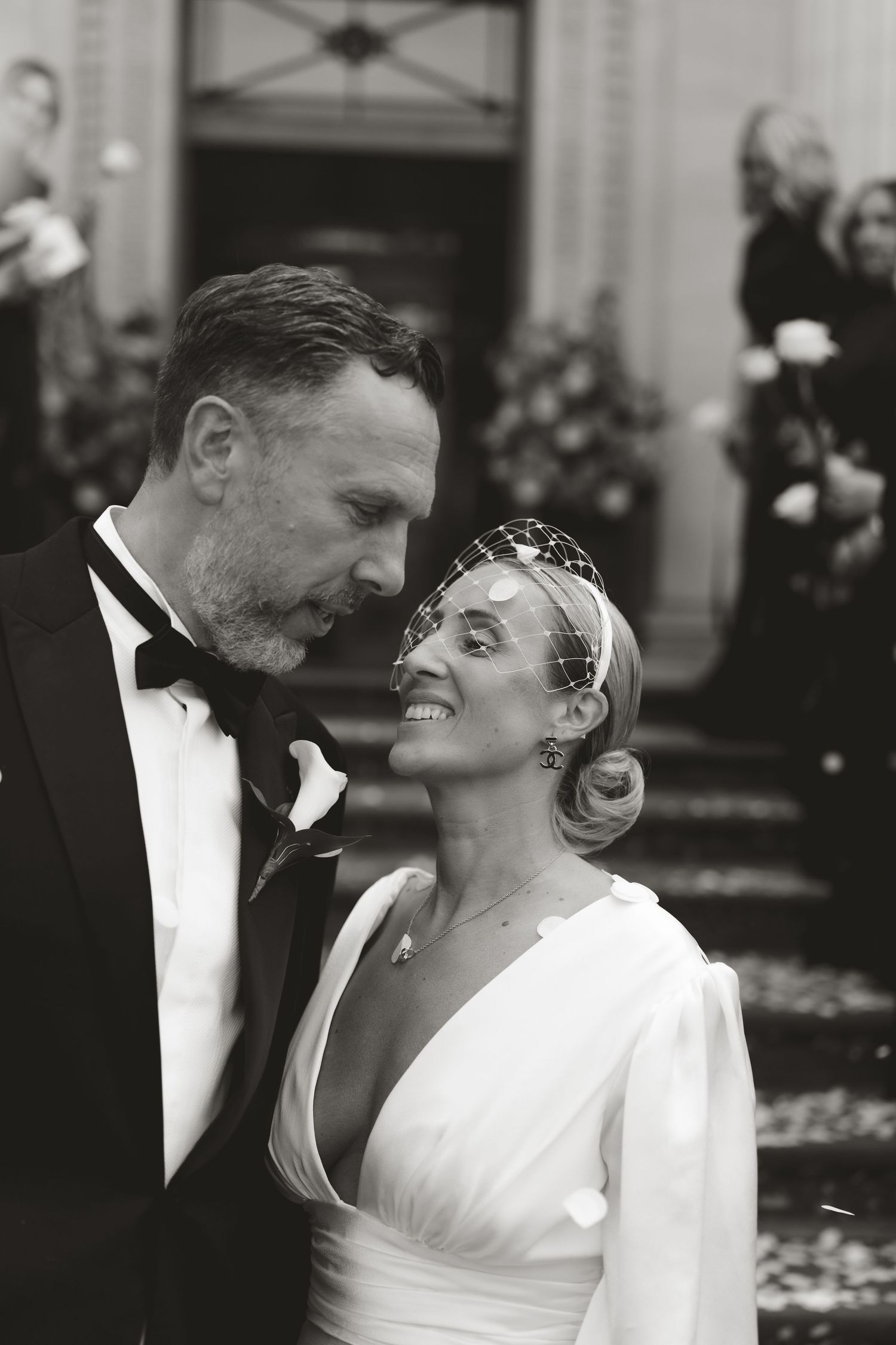 Black and white photo of newlyweds sharing an intimate moment in their formal wedding attire.
