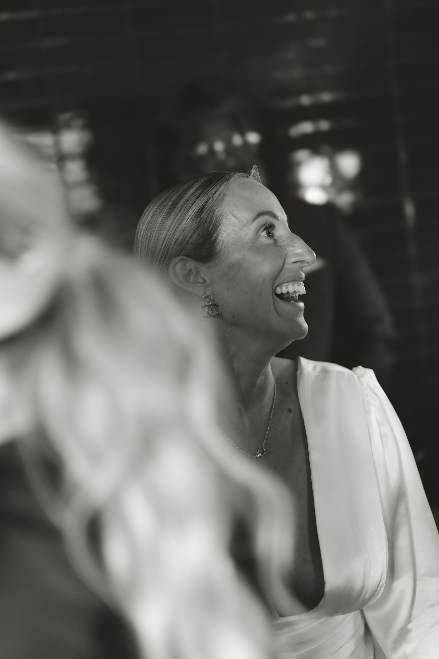 A series of black and white candid photos showing joyful laughter at a formal wedding event.