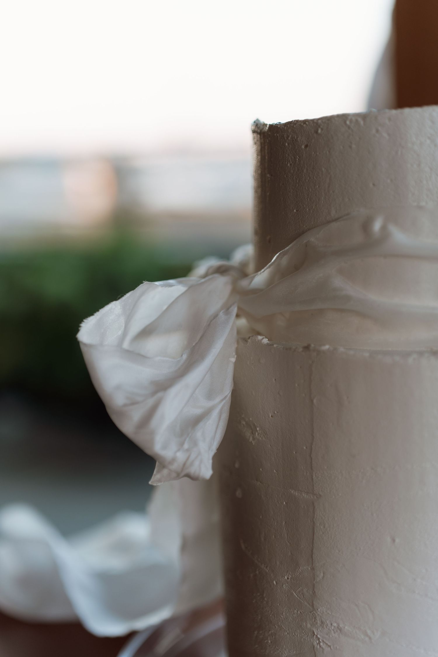 Close-up detail of white frosting texture on a wedding cake with soft lighting and blurred background.