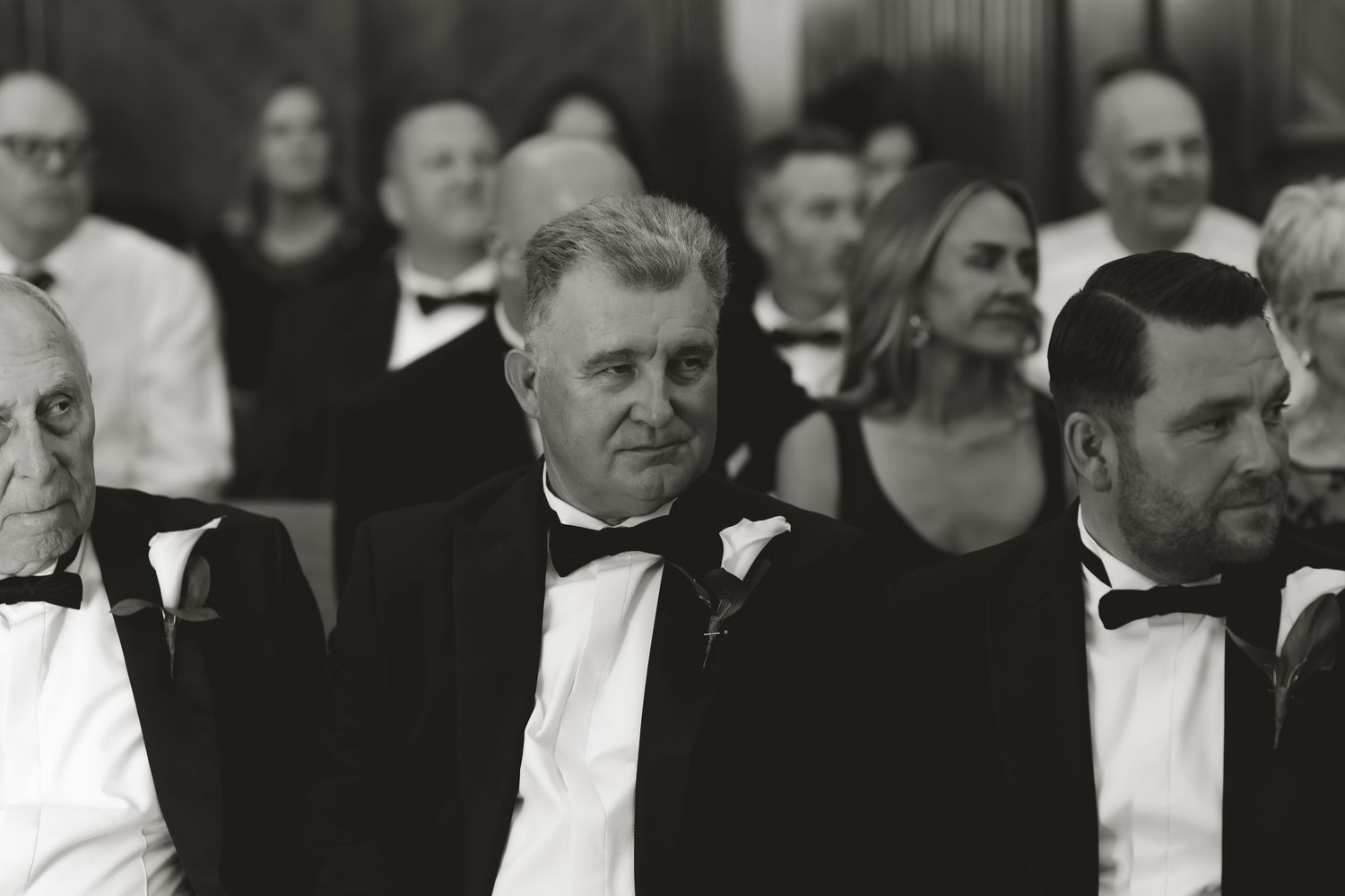 A vintage black and white photograph showing a large formal gathering at an event dressed in tuxedos and bow ties.