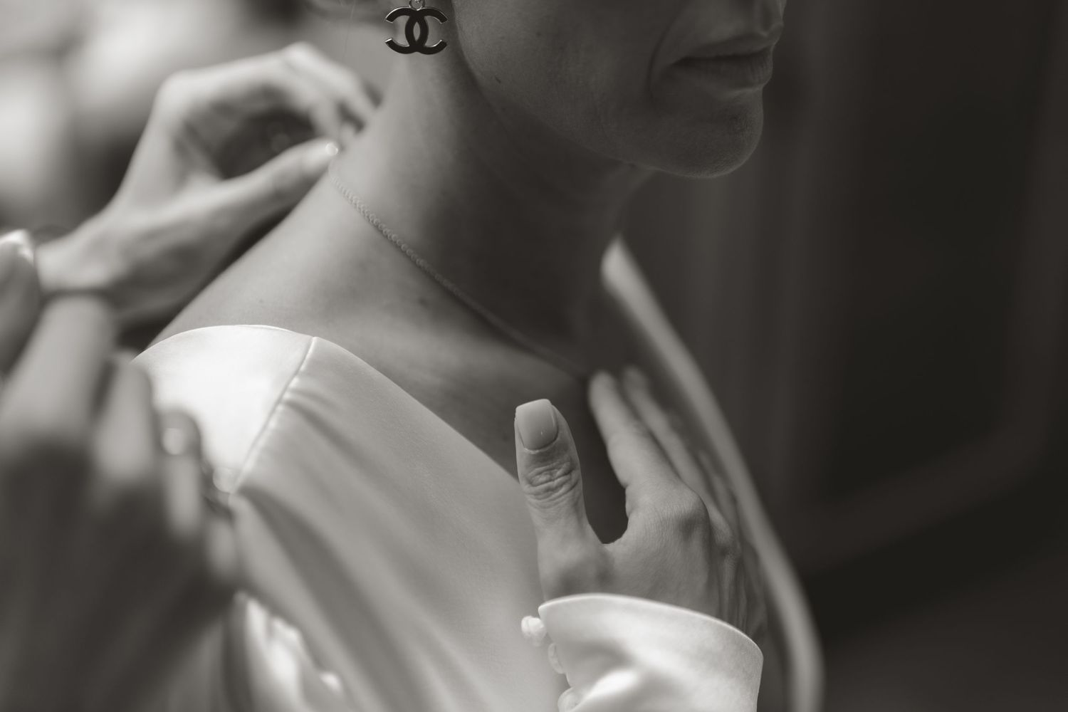 A black and white fashion advertisement shows elegant hands holding Chanel beauty products in an artistic composition.
