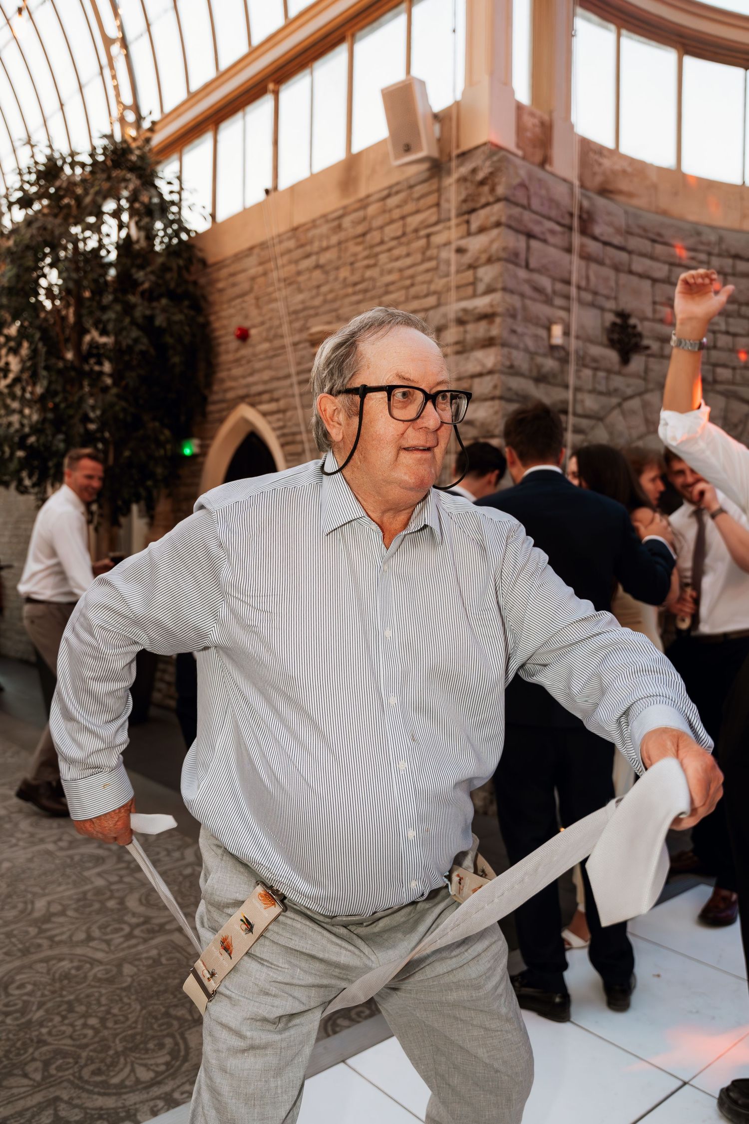 Wedding guest dancing enthusiastically on a dance floor during a reception celebration.