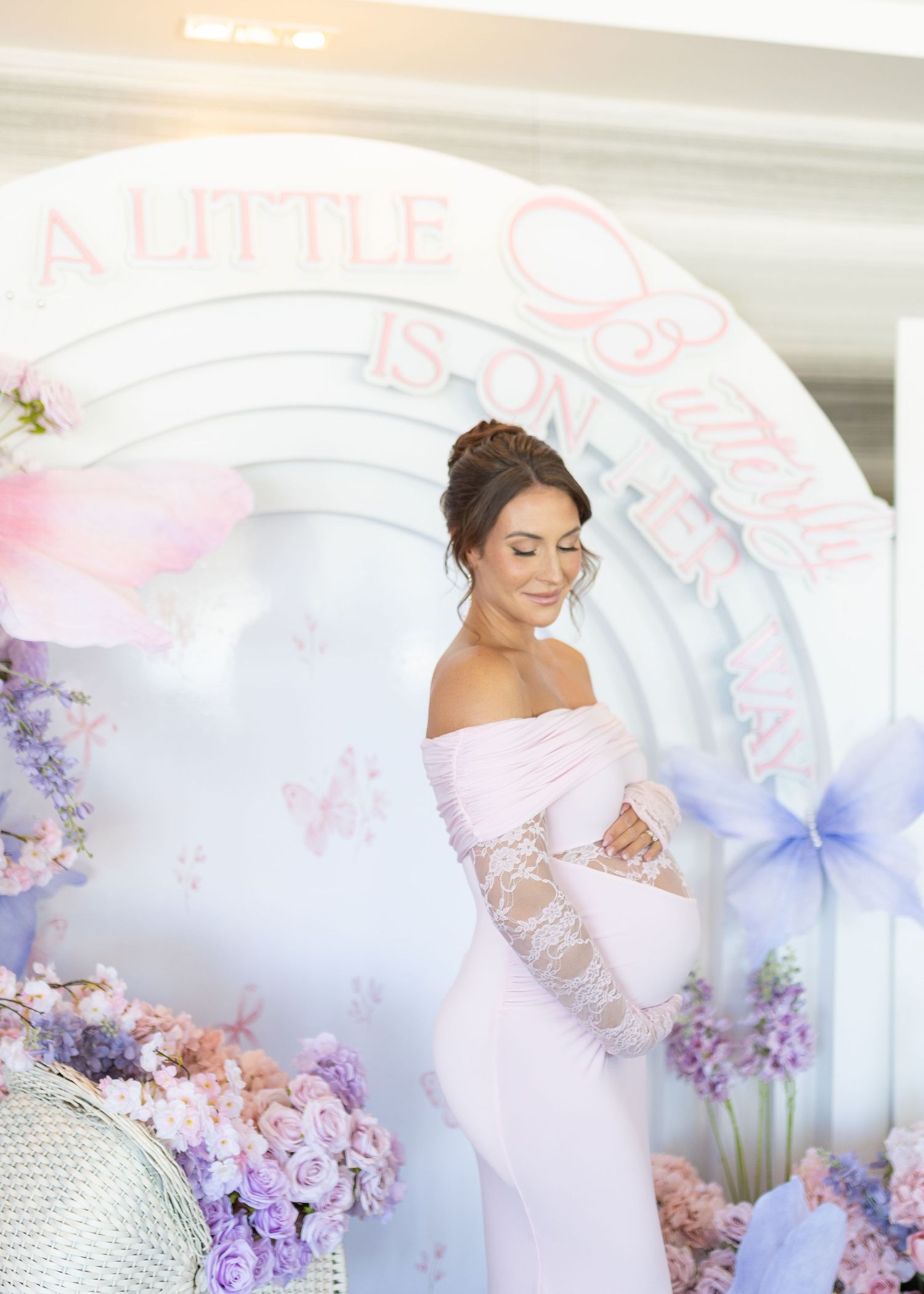 Mom-to-be holding her belly at her pink and purple butterfly baby shower at Harbor Club at Prime in Huntington, New York.