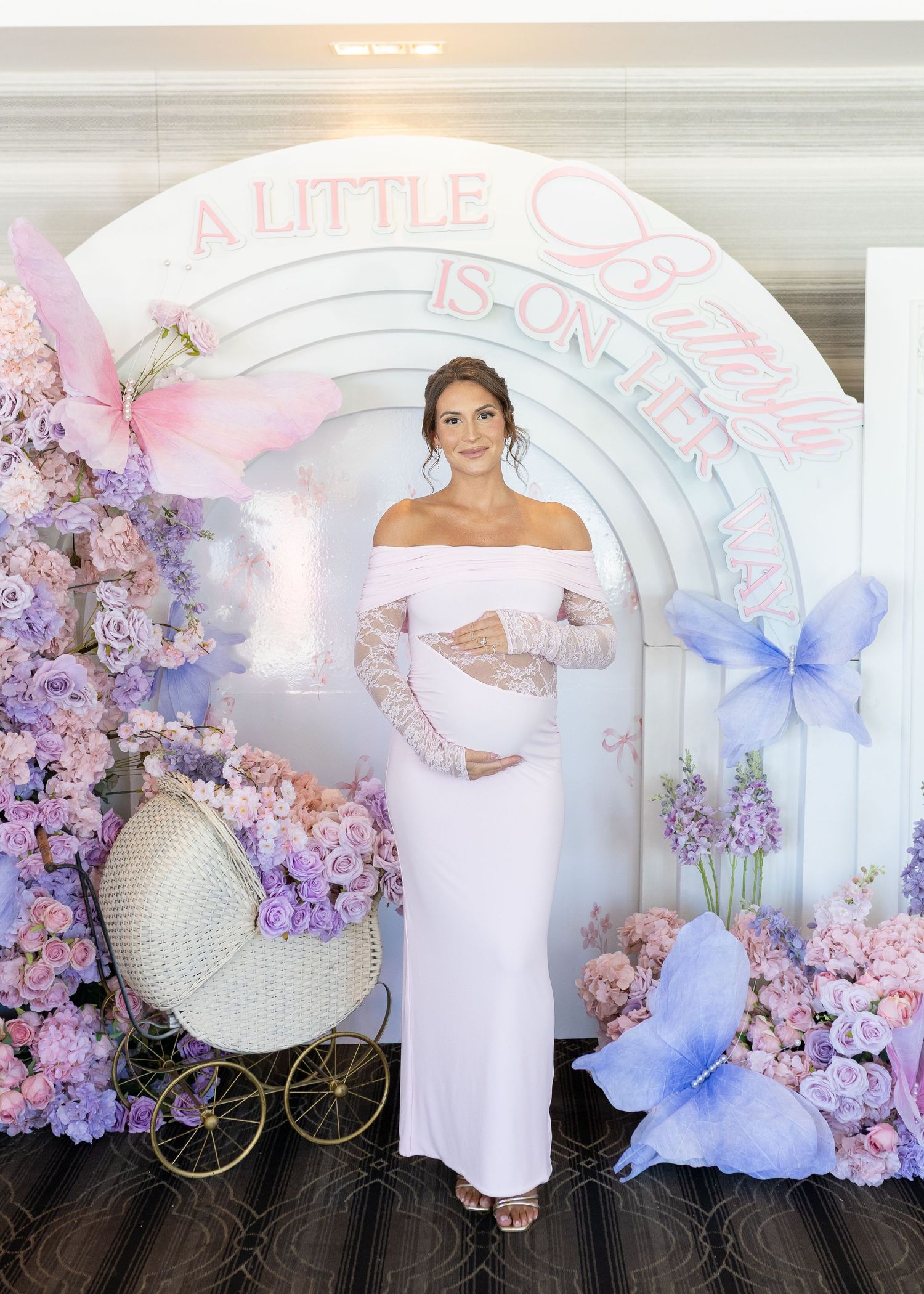 Mom-to-be holding her belly at her pink and purple butterfly baby shower at Harbor Club at Prime in Huntington, New York.