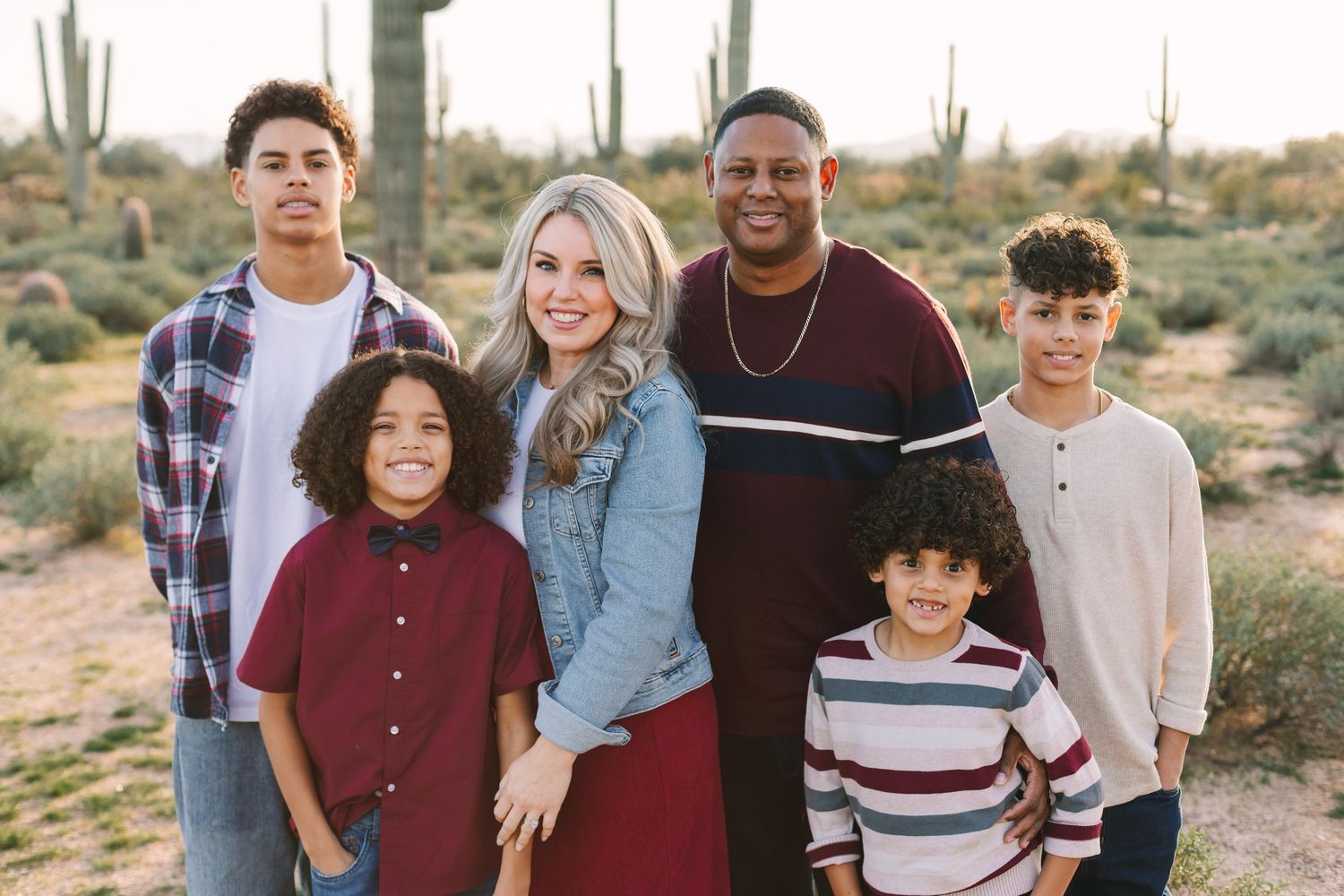 Blended family of six smiling together outdoors in the Arizona desert with cacti in background.