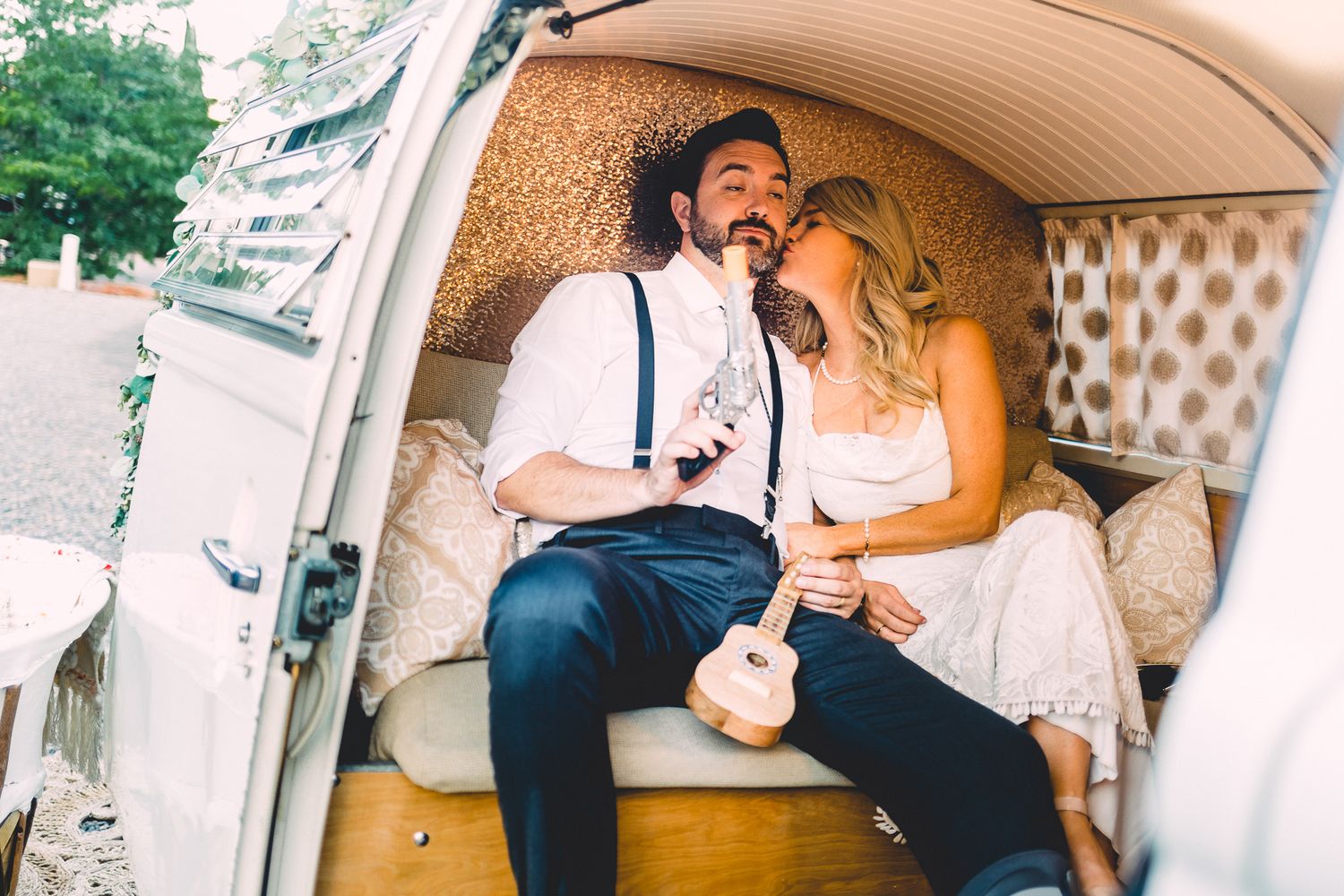 Happy couple sitting inside a vintage van, sharing a romantic moment with a ukulele.