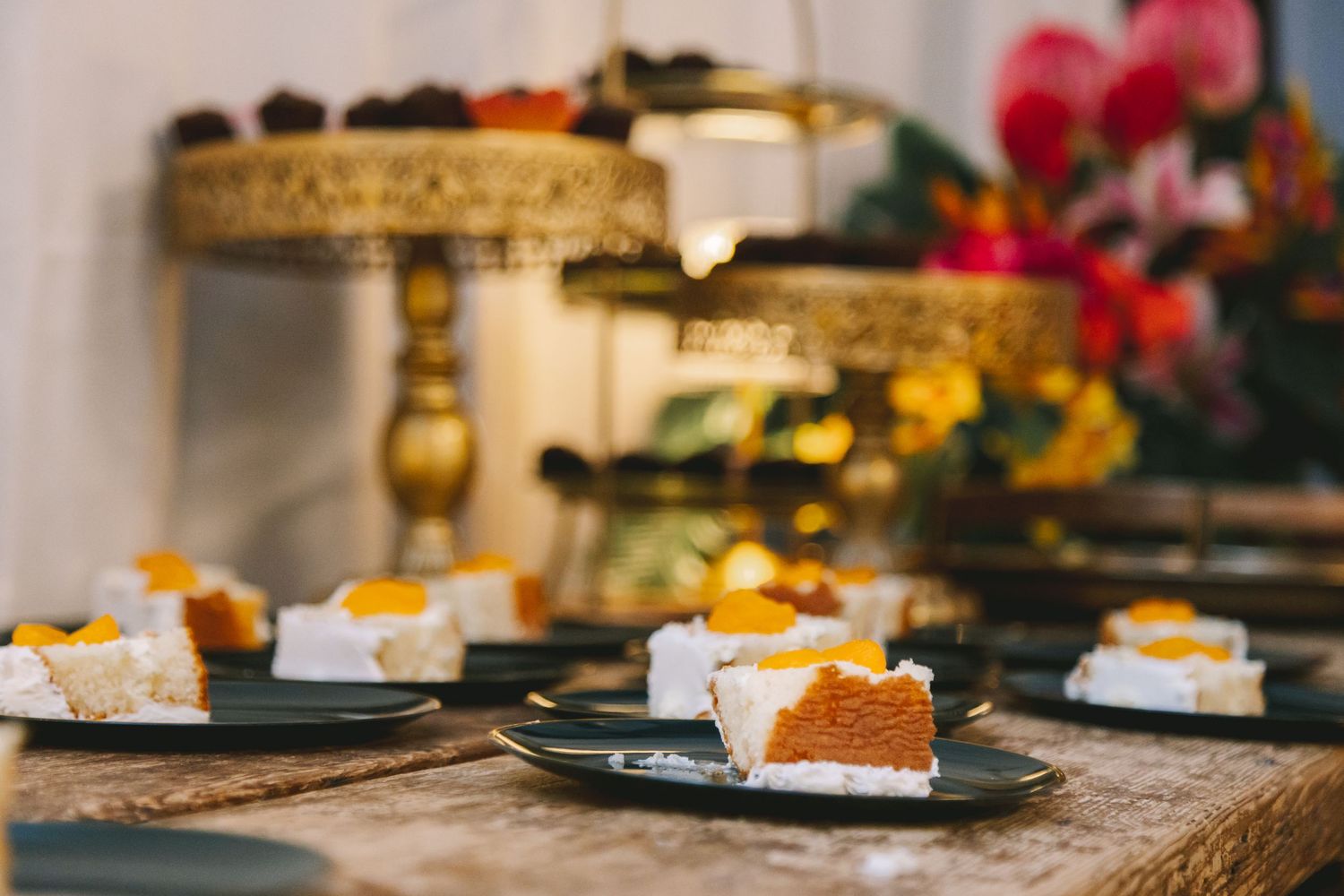 Elegant dessert table with sliced cake pieces on dark plates at a wedding reception.