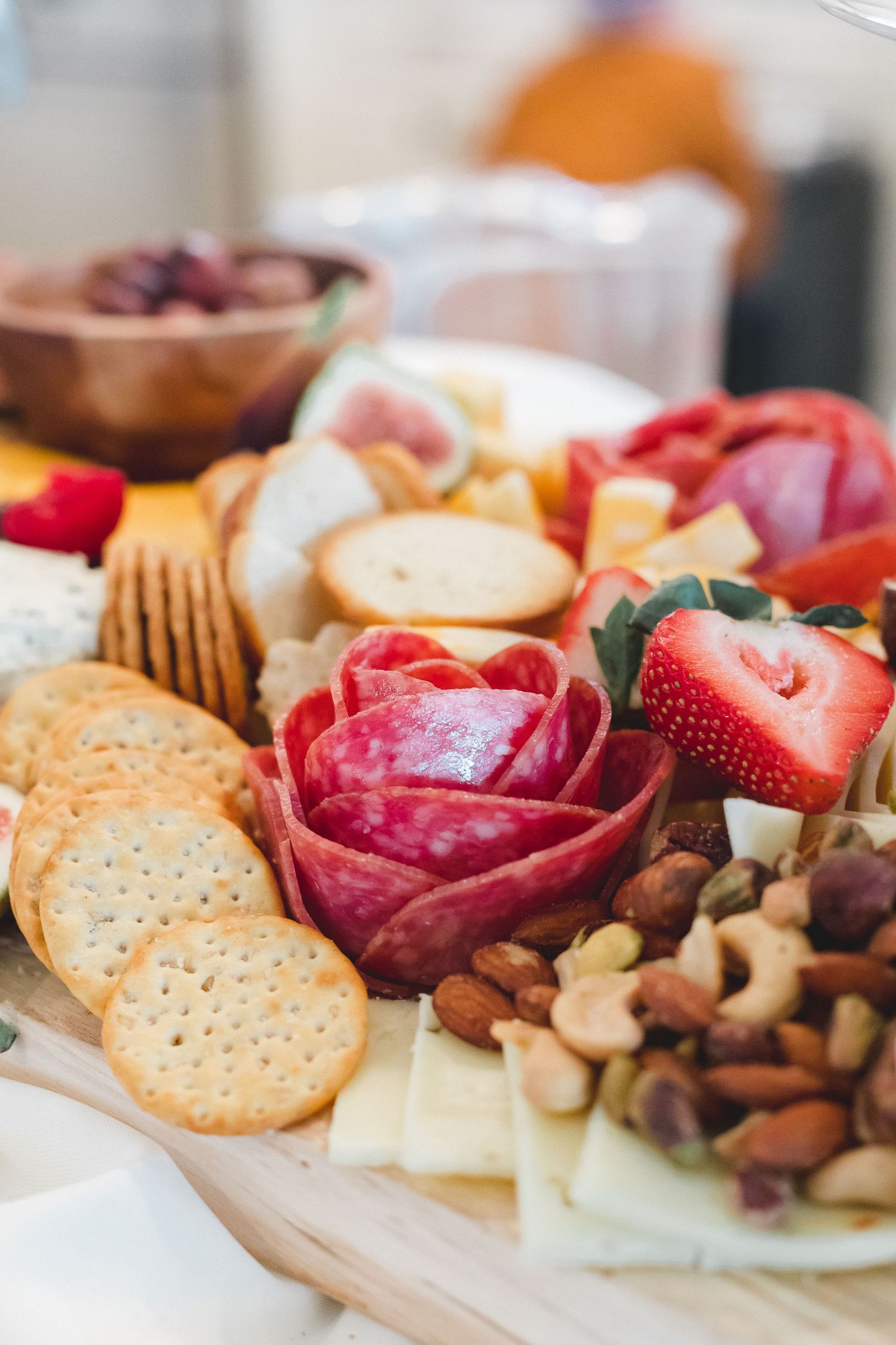 Elegant charcuterie board with salami roses, fresh strawberries, mixed nuts, crackers, and cheese for a wedding reception.