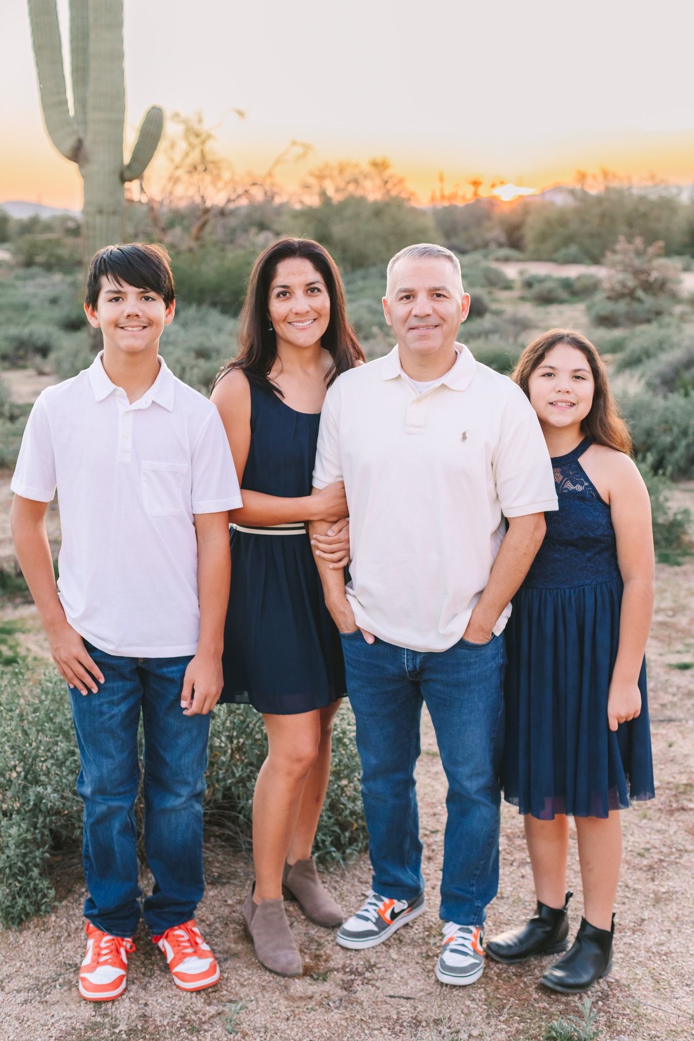 Family of four posing at sunset in the Arizona desert with a saguaro cactus in background.