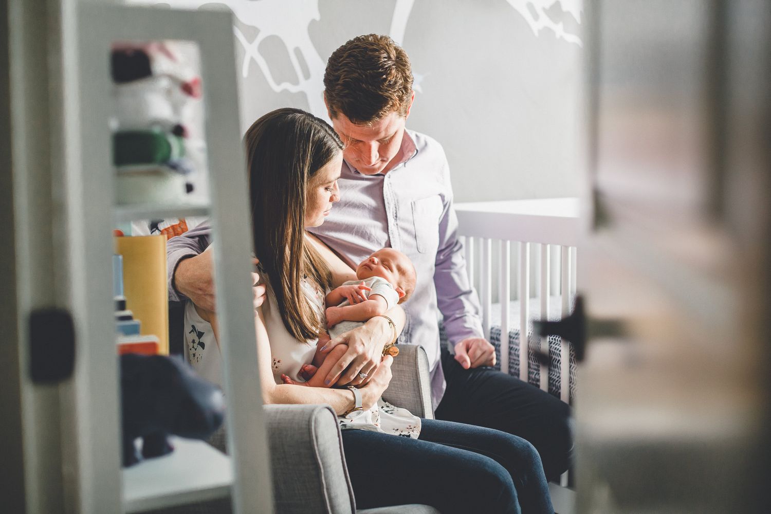 New parents holding newborn baby in nursery room.