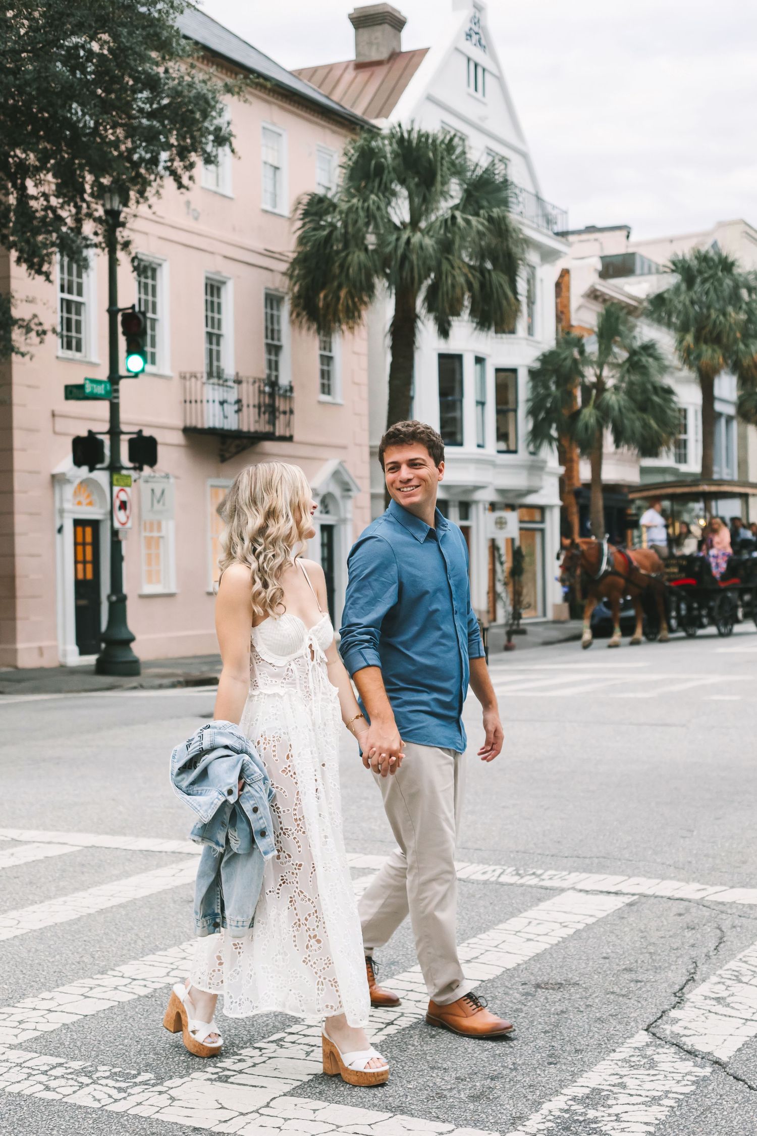 Couple holding hands while crossing a street in historic Charleston, South Carolina on a cloudy day.