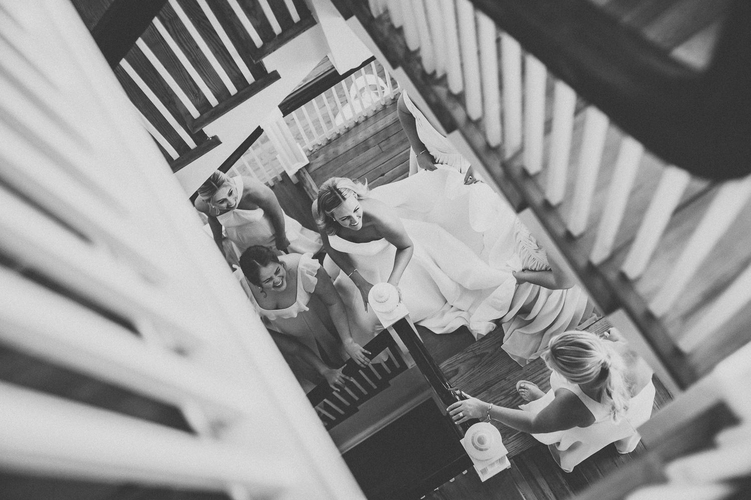 Aerial black and white photo of wedding party gathered on staircase during bridal preparations.