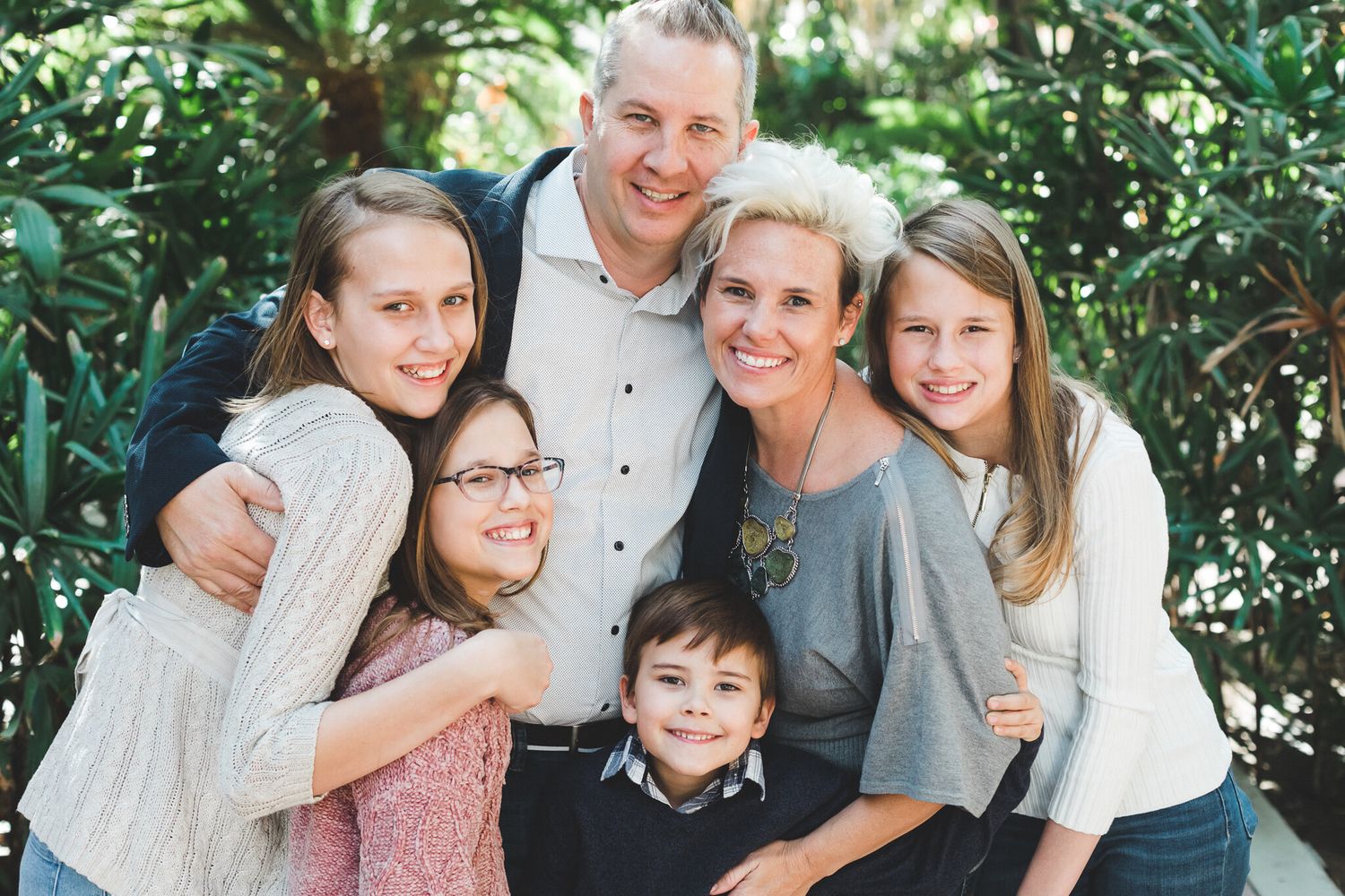 Happy family of six smiling together in lush garden.