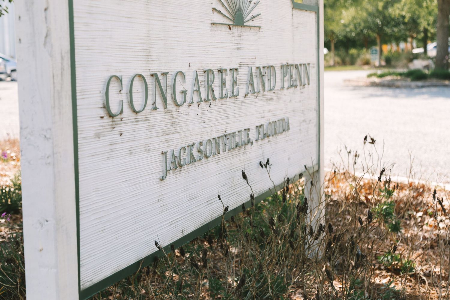Close-up of weathered white wooden Congaree and Penn Jacksonville Florida venue entrance sign.