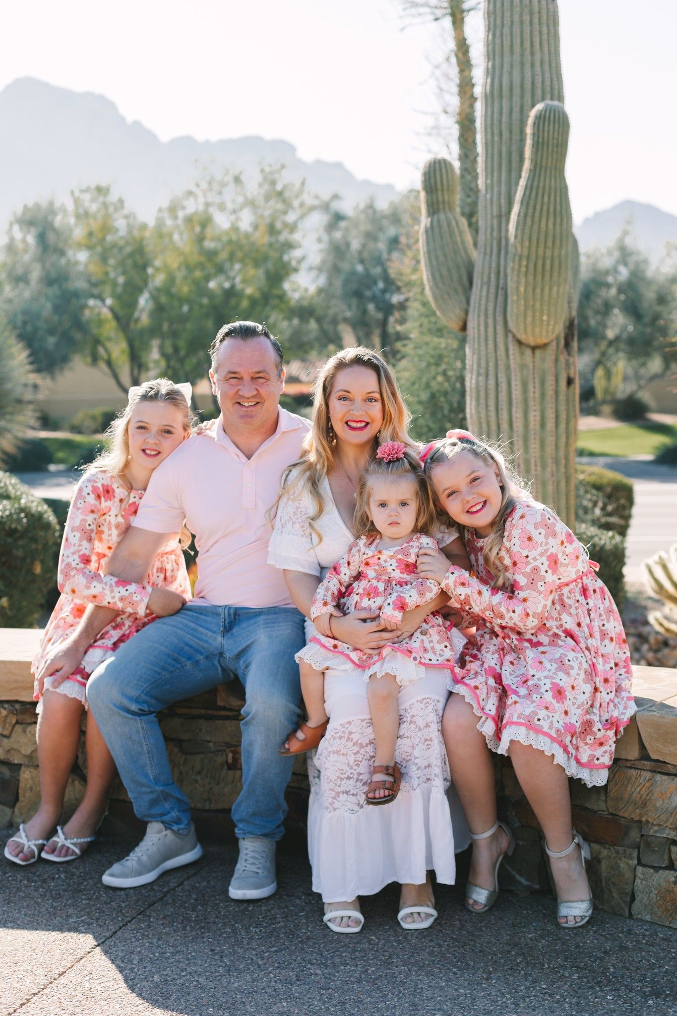 Family of five in matching pink floral outfits posing near saguaro cactus in Arizona.