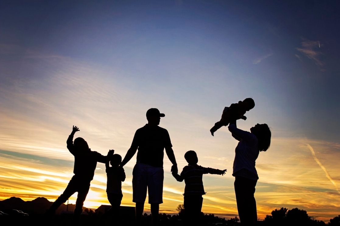 Silhouette of family with children playing at sunset.