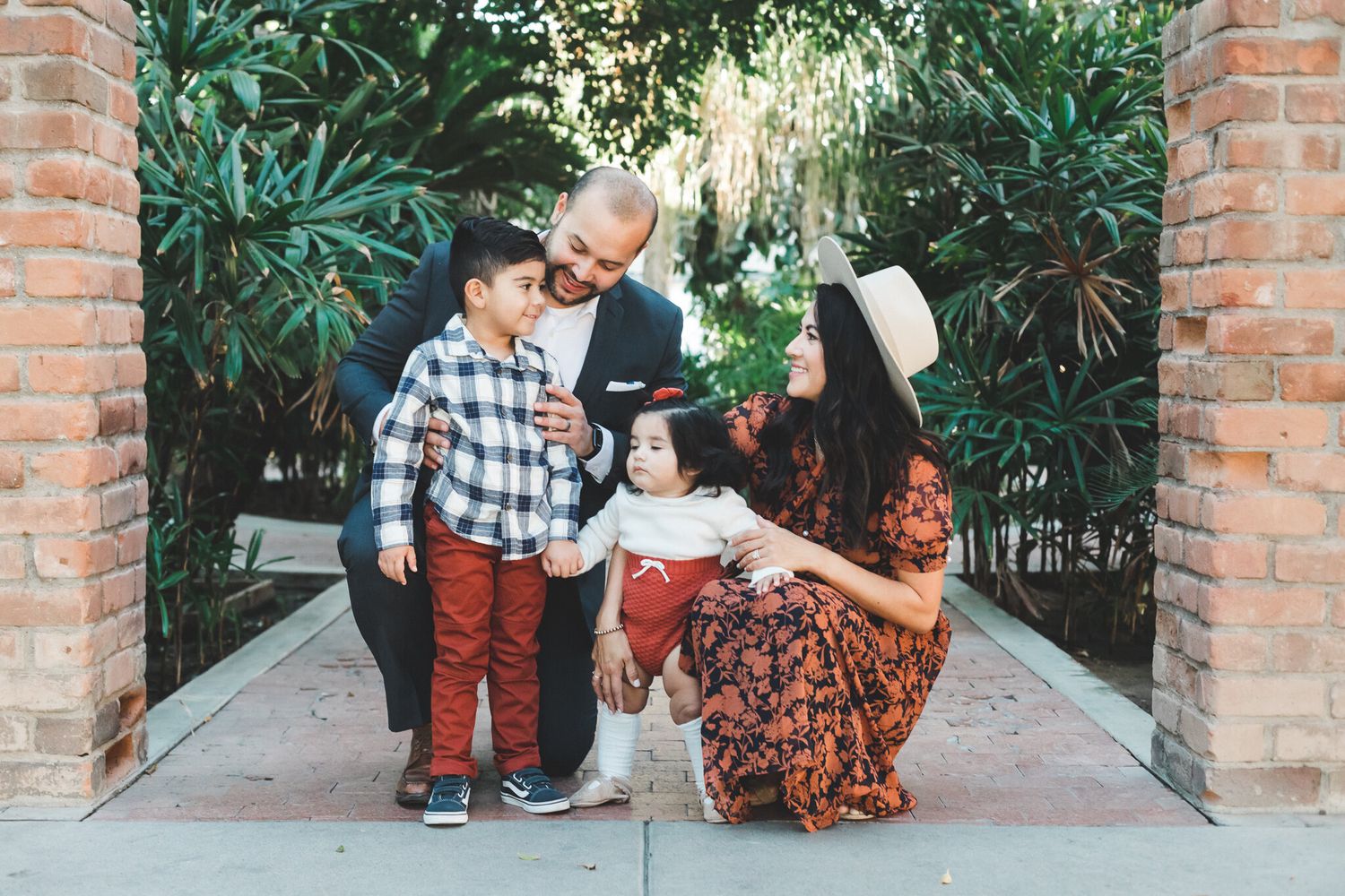 Young Hispanic family with two children in garden archway.