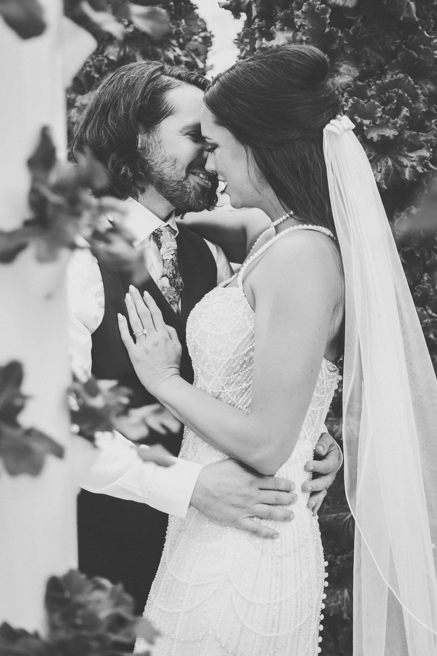 Black and white romantic portrait of bride and groom embracing and smiling at each other.