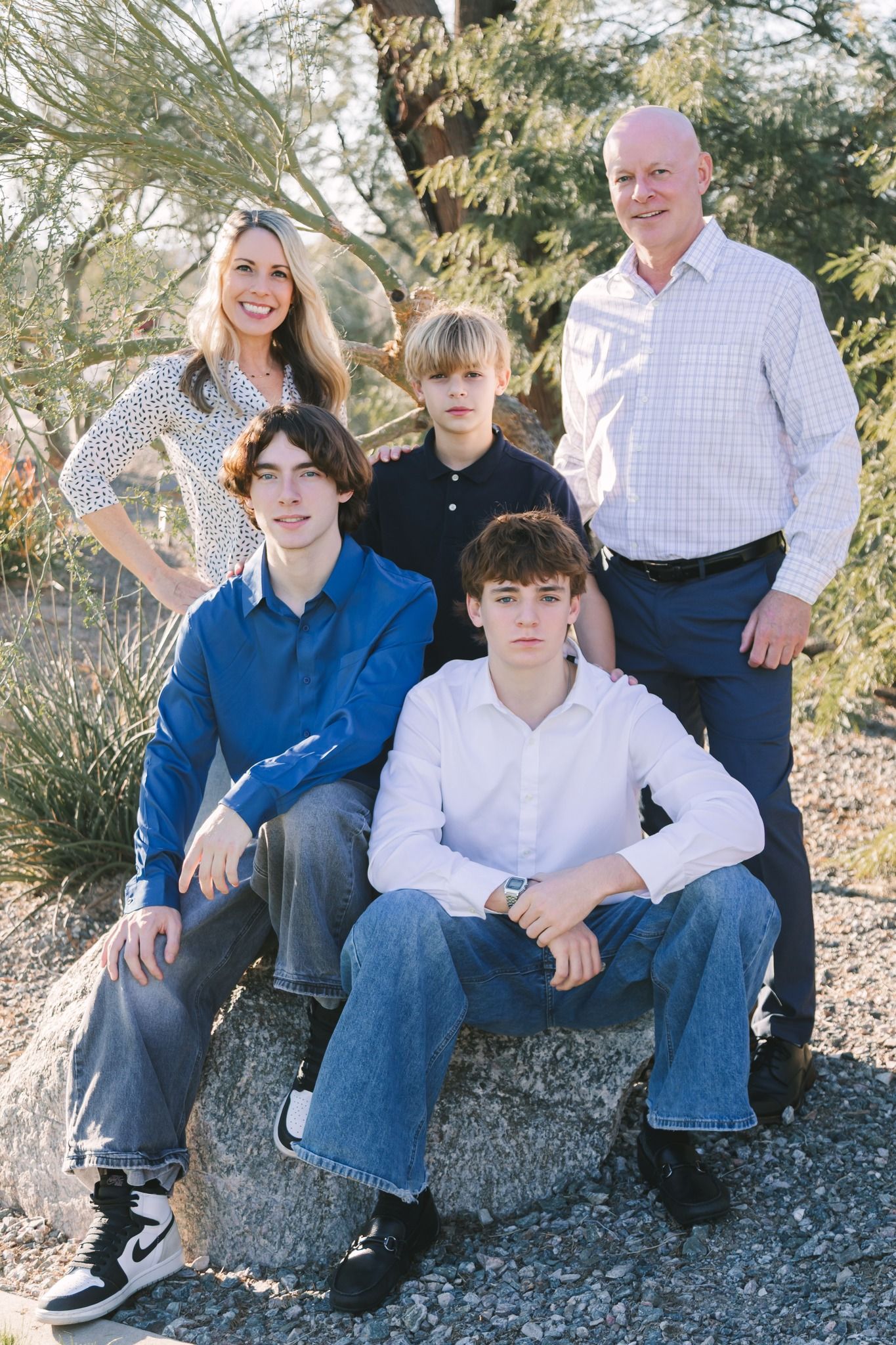 Family of five with three teenage boys pose on rocks in desert garden setting.
