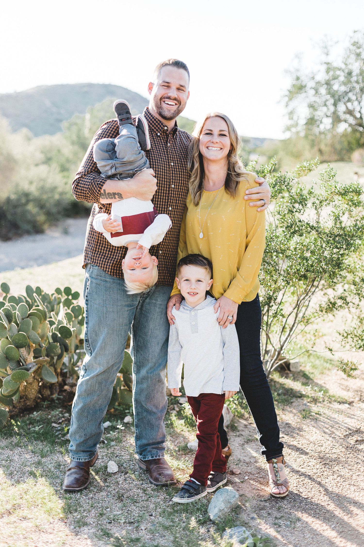 Smiling family of four posing outdoors near desert cacti.