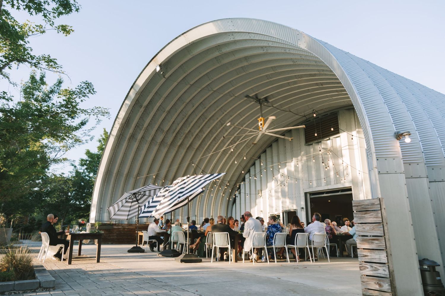 Wedding reception guests dining under a curved metal Quonset hut venue at Congaree and Penn Jacksonville.