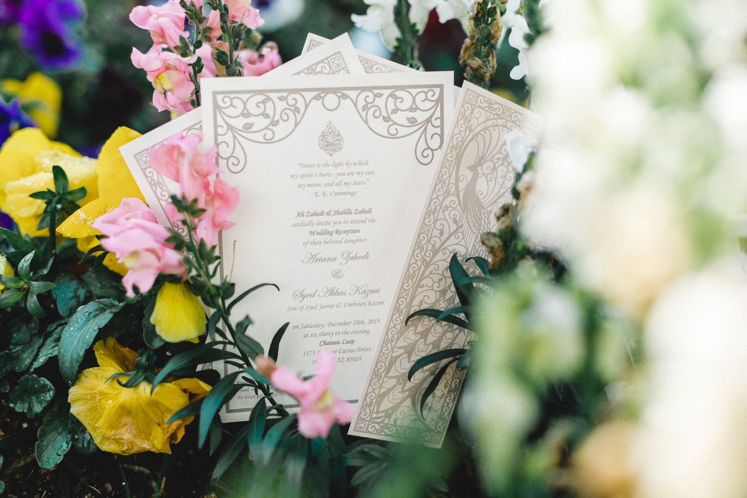 Elegant South Asian wedding invitation with floral laser-cut design displayed among colorful garden flowers.