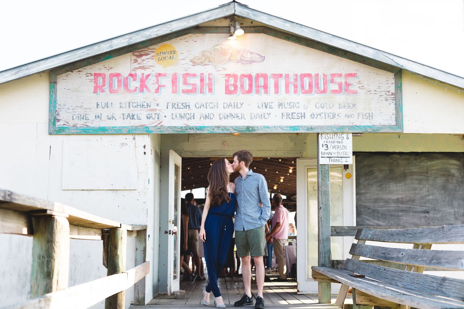 Couple kissing in the entrance of Rockfish Boathouse on a sunny day.