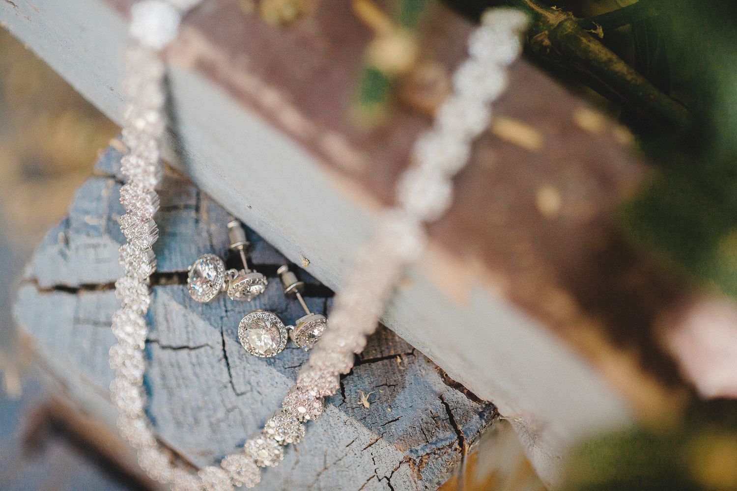 Elegant pearl necklace and diamond stud earrings displayed on rustic weathered wood.