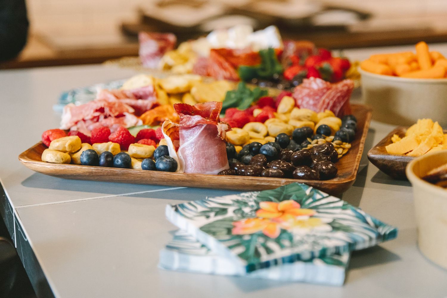 Elegant wedding charcuterie board with meats, fruits, and crackers on reception table.