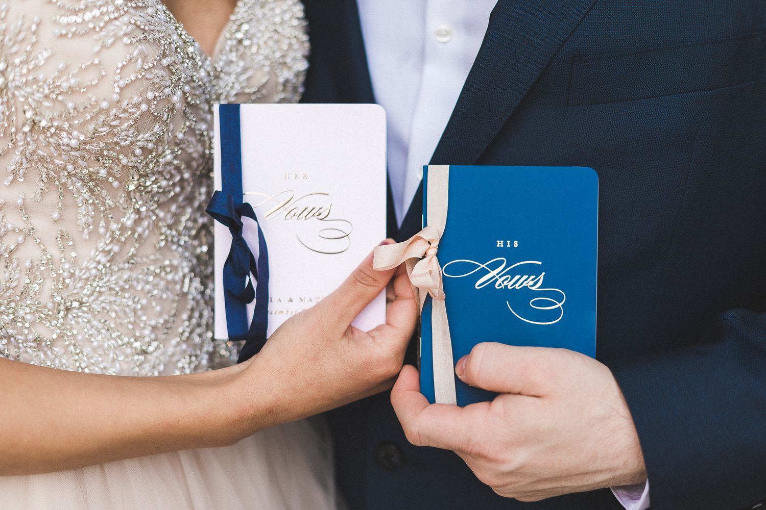 Bride and groom holding matching navy and white personalized wedding vow books.