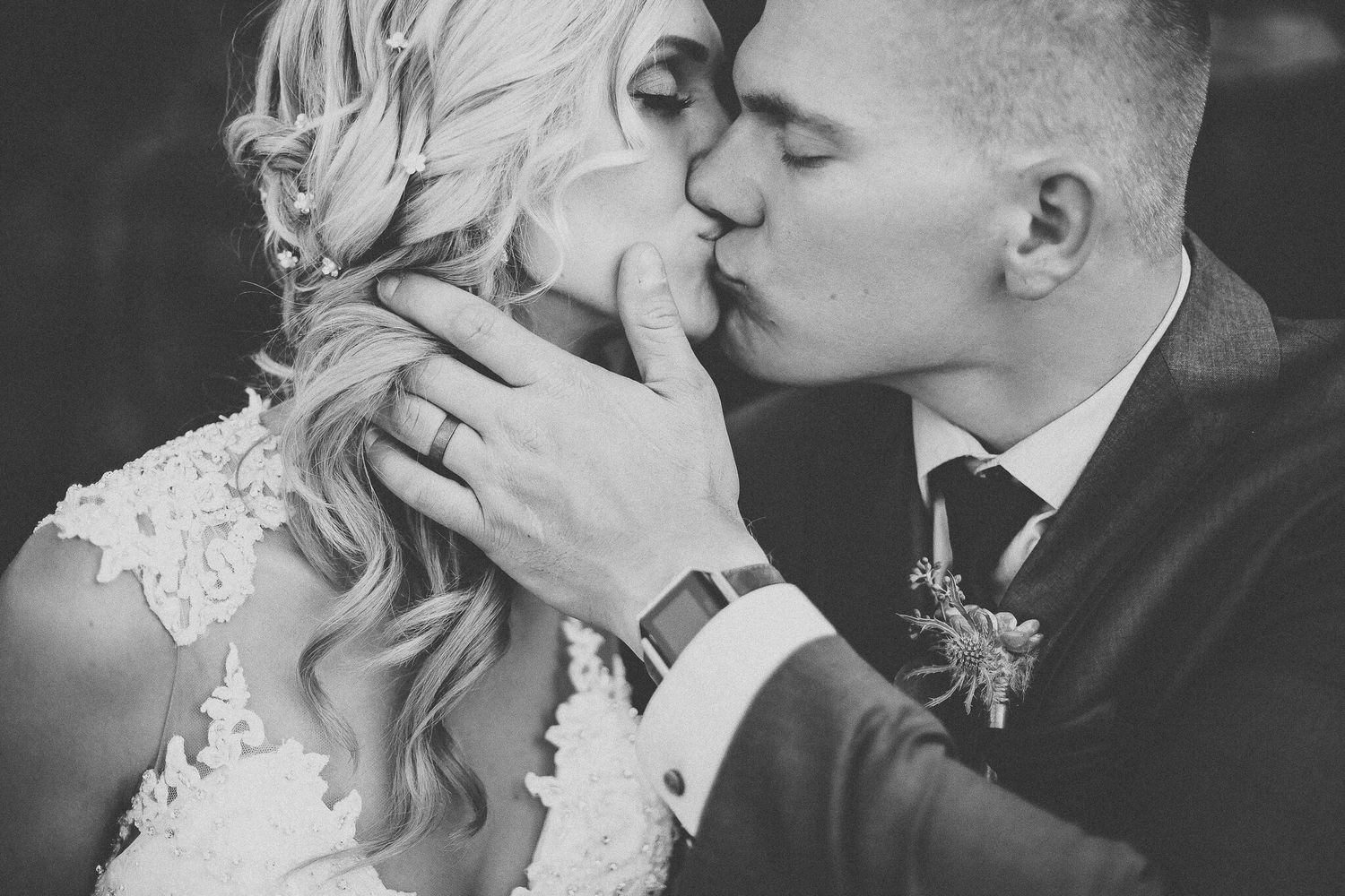 Black and white close-up of newlywed couple sharing a tender kiss after wedding ceremony.