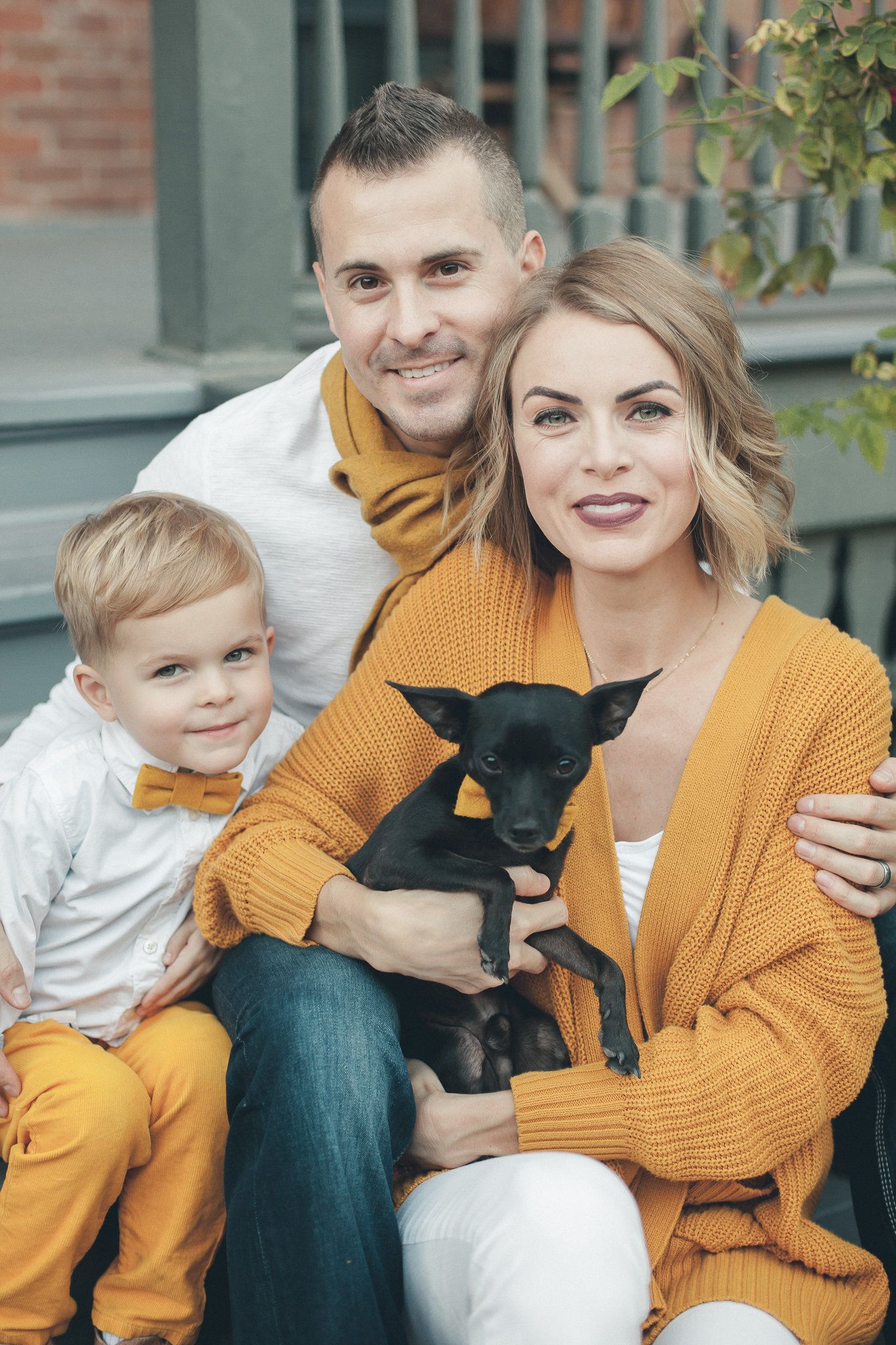 Happy family with boy and black dog wearing matching yellow outfits.