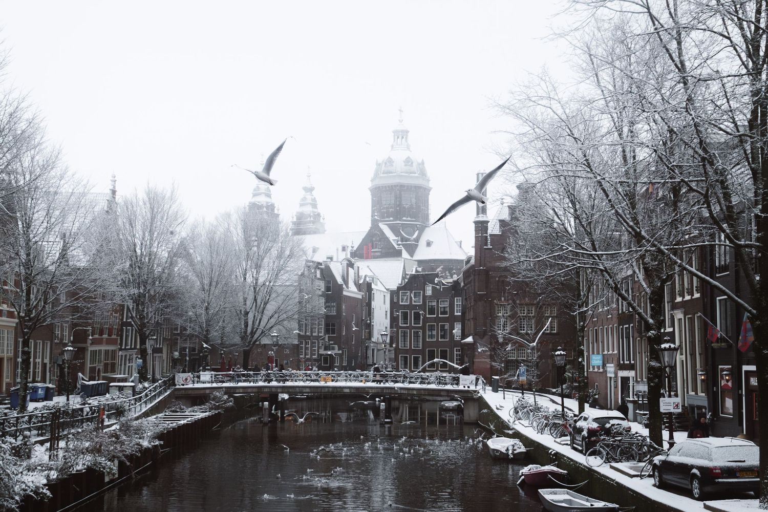 Snowy street photography in Amsterdam capturing the city covered in snow with soft light and a quiet winter atmosphere.