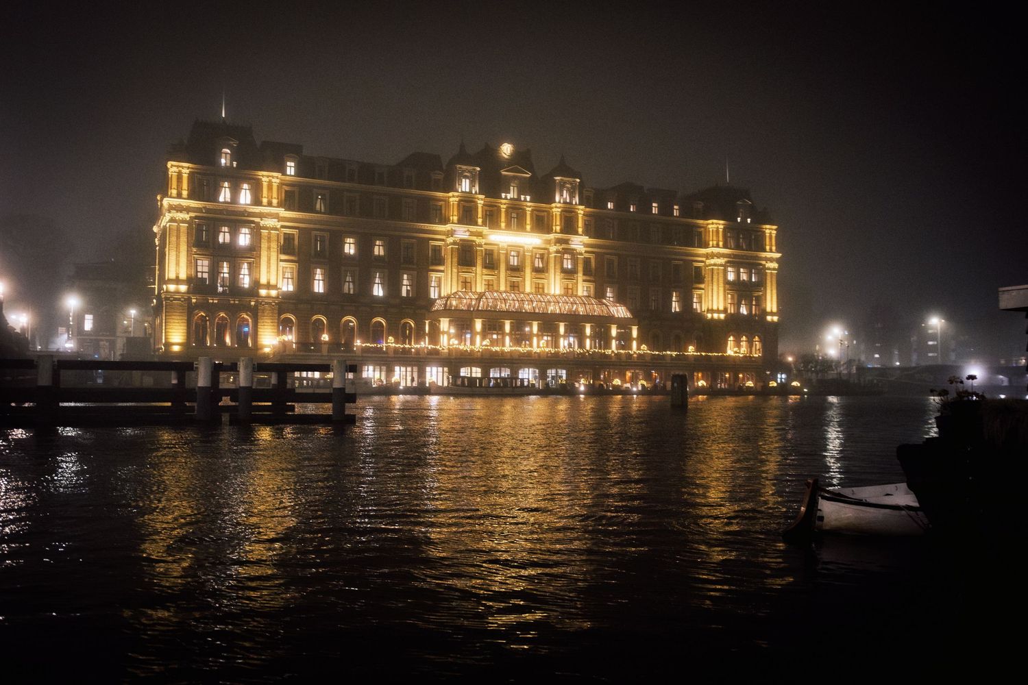 Night street photography in Amsterdam showing the city in heavy mist with soft lights, reflections and a cinematic urban atmosphere.
