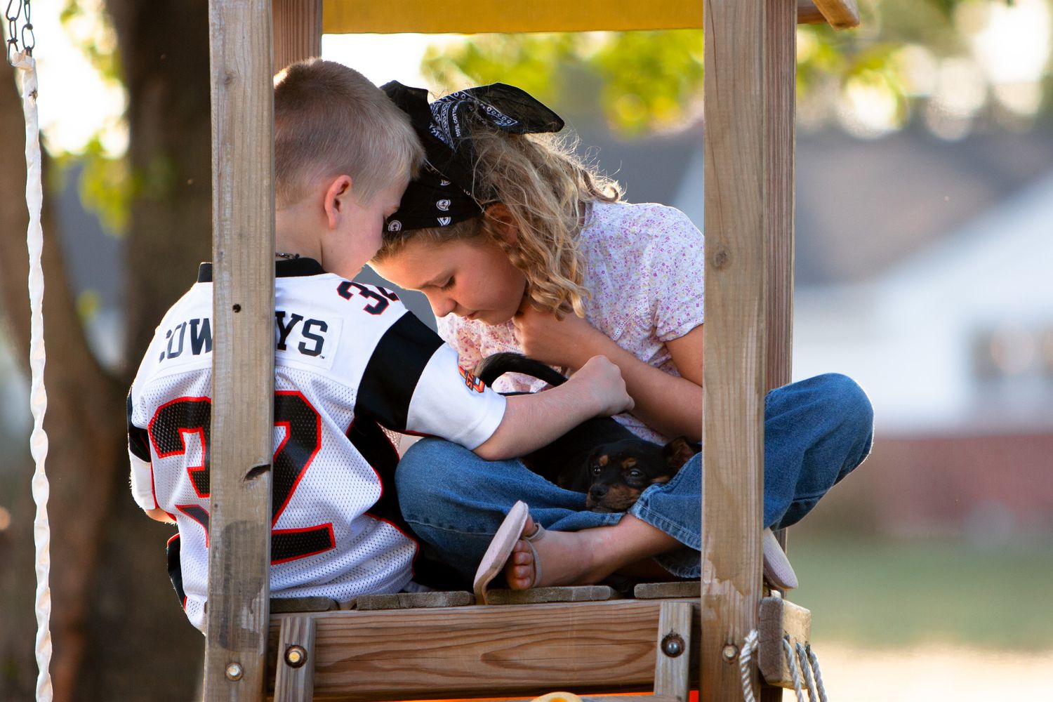 Two kids cuddle a cute dog in a playset in Kansas