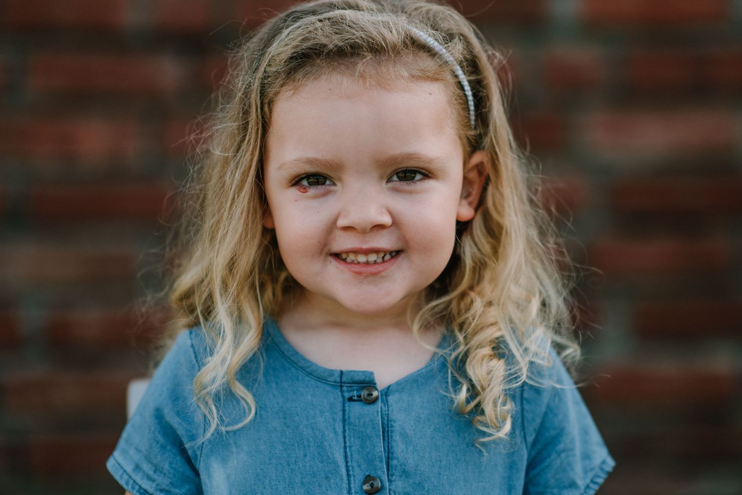 Portrait against brick wall background wearing blue clothing.