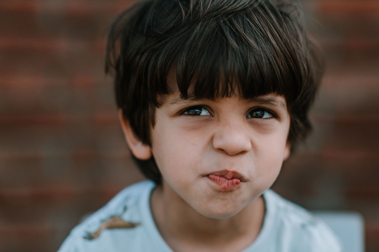 Close-up portrait against brick wall background.
