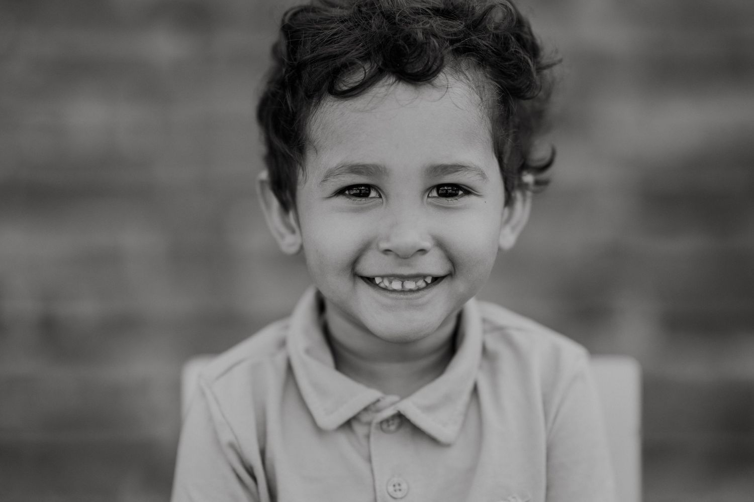 Black and white portrait with genuine smiles against textured wall.