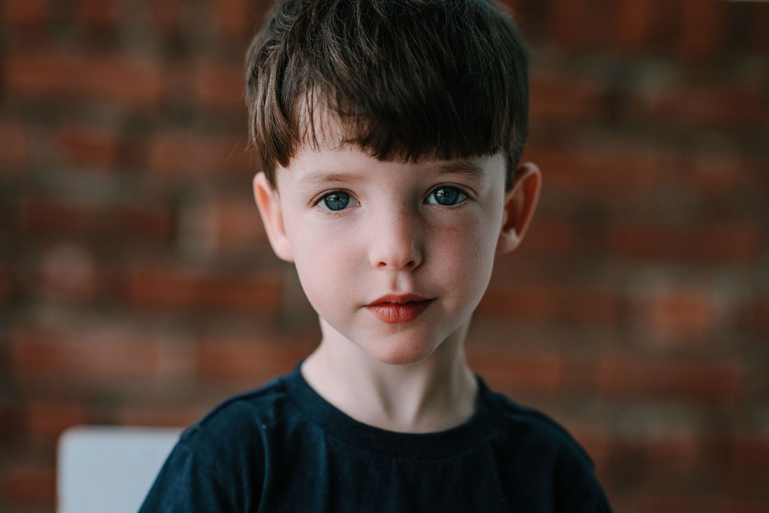 A series of close-up portraits showing different playful expressions against a brick wall background.