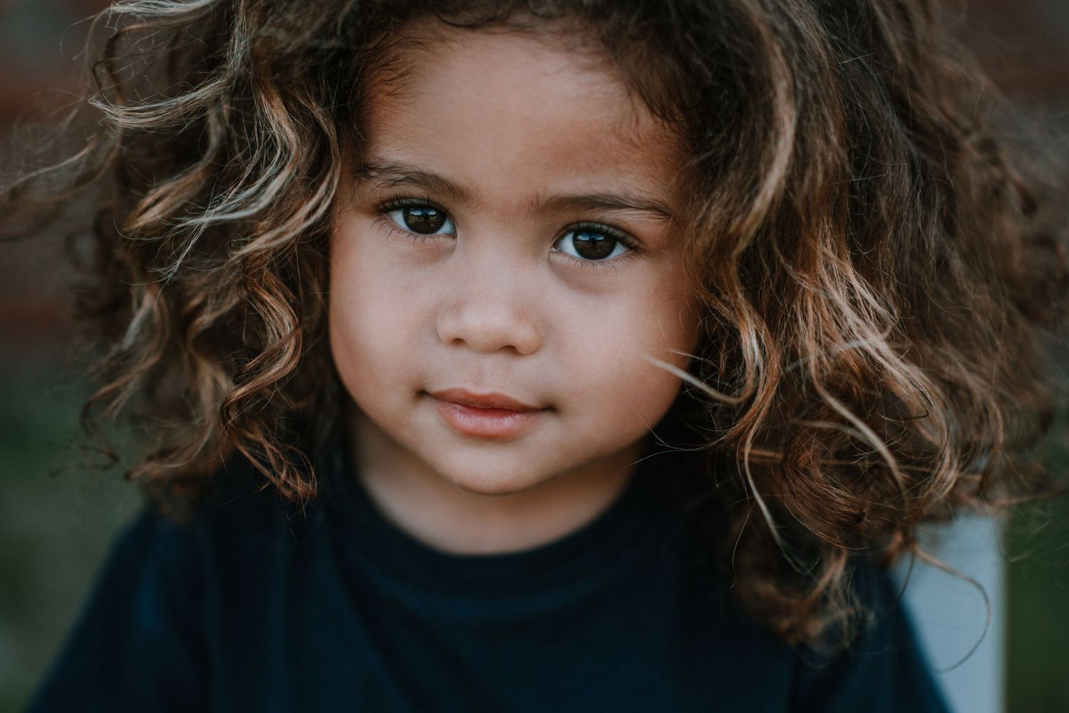 Portrait showcasing natural expressions against brick backdrop.