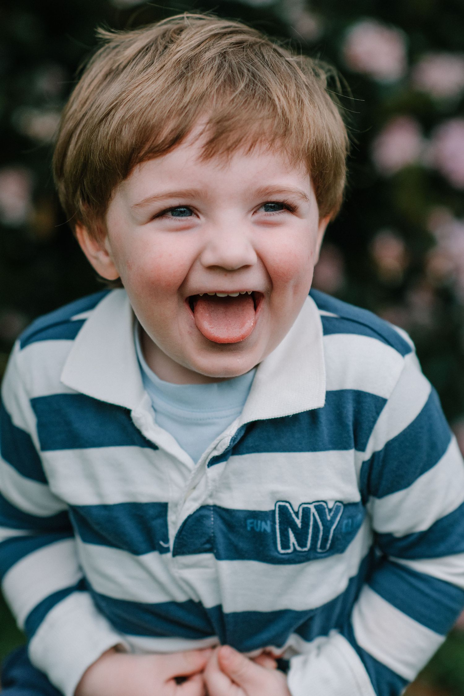 Candid portrait of a child wearing a blue and white striped shirt outdoors.