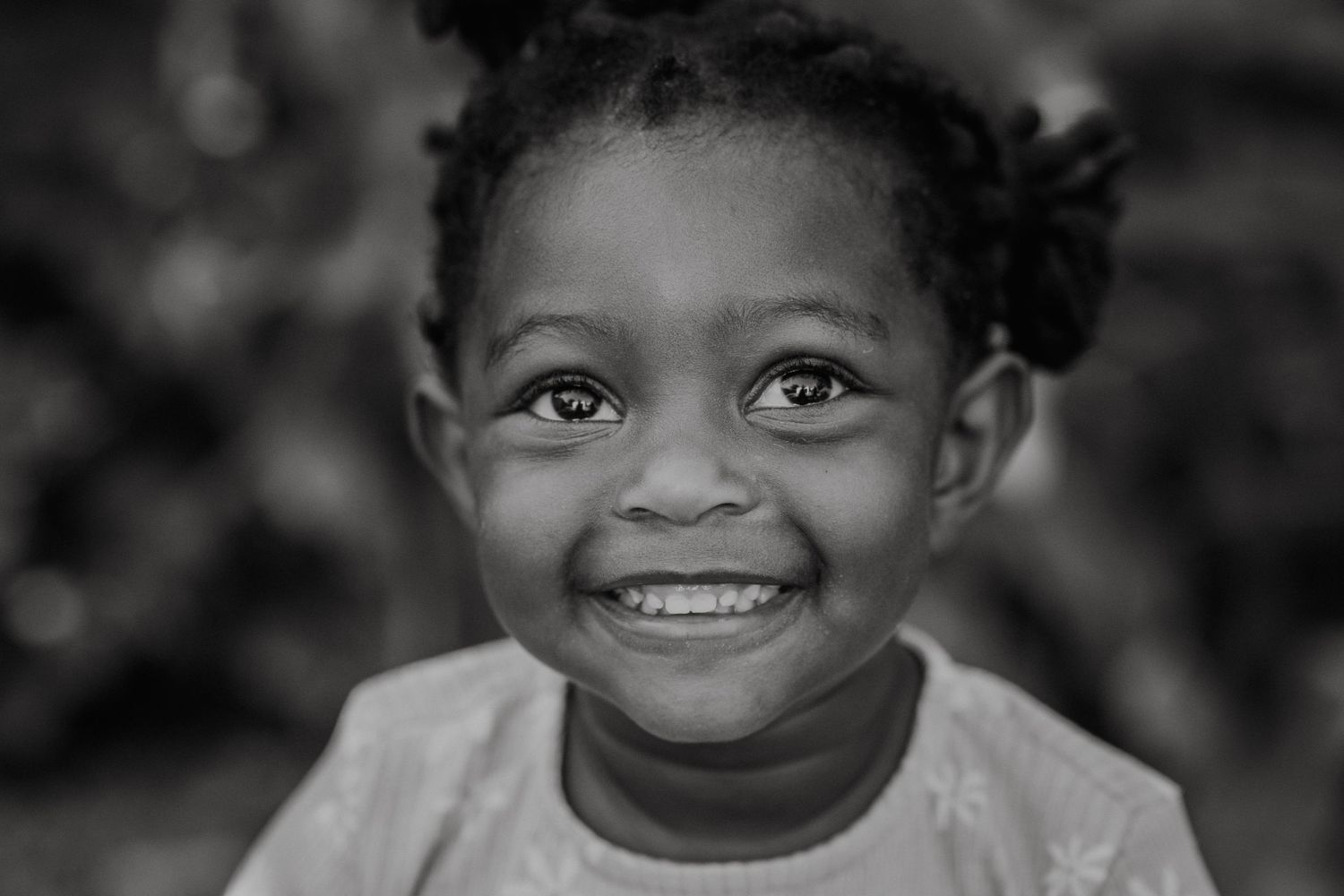 Black and white close-up portrait showing bright smile and joyful expression.