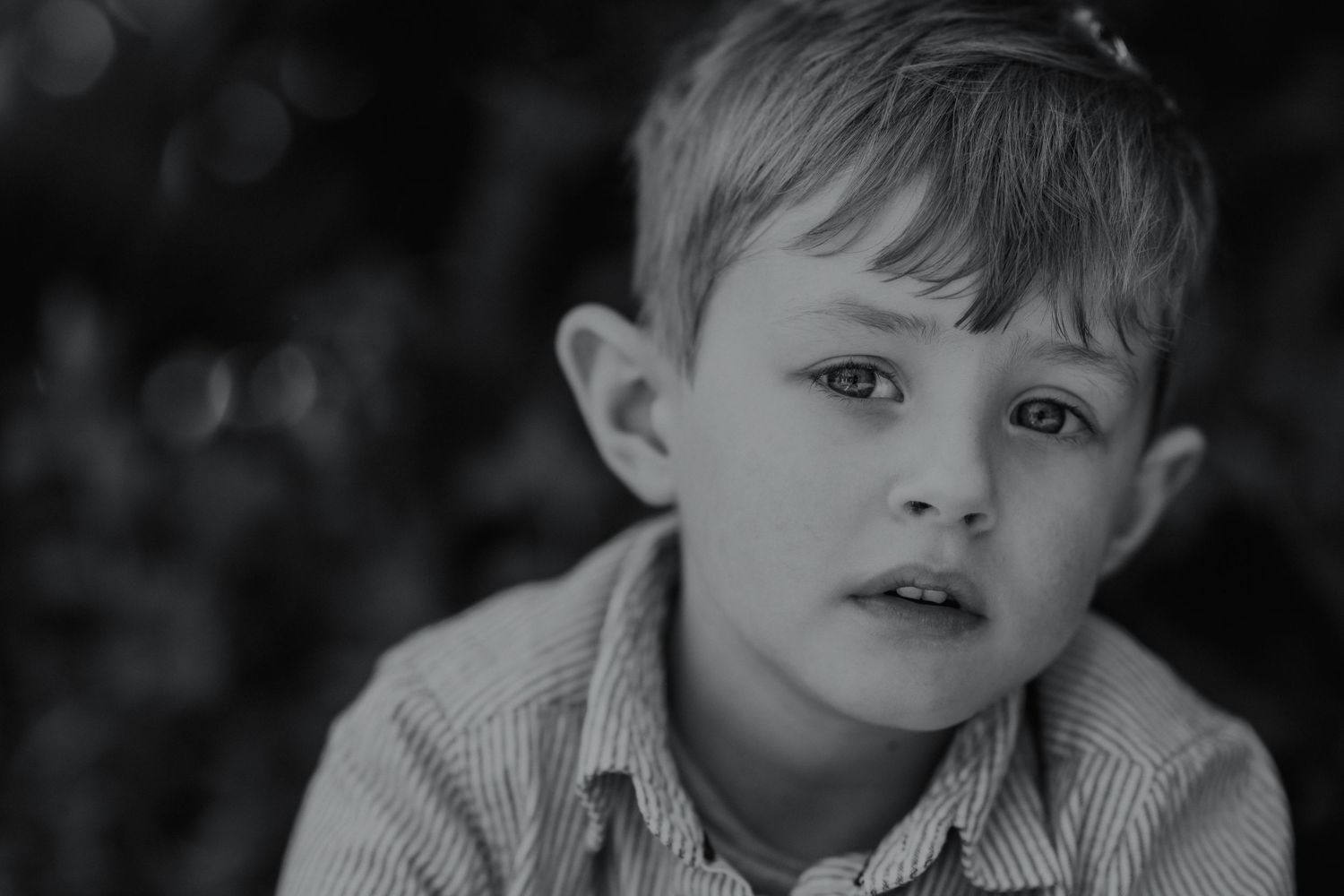 Black and white portrait of a child in striped collar with thoughtful expression.
