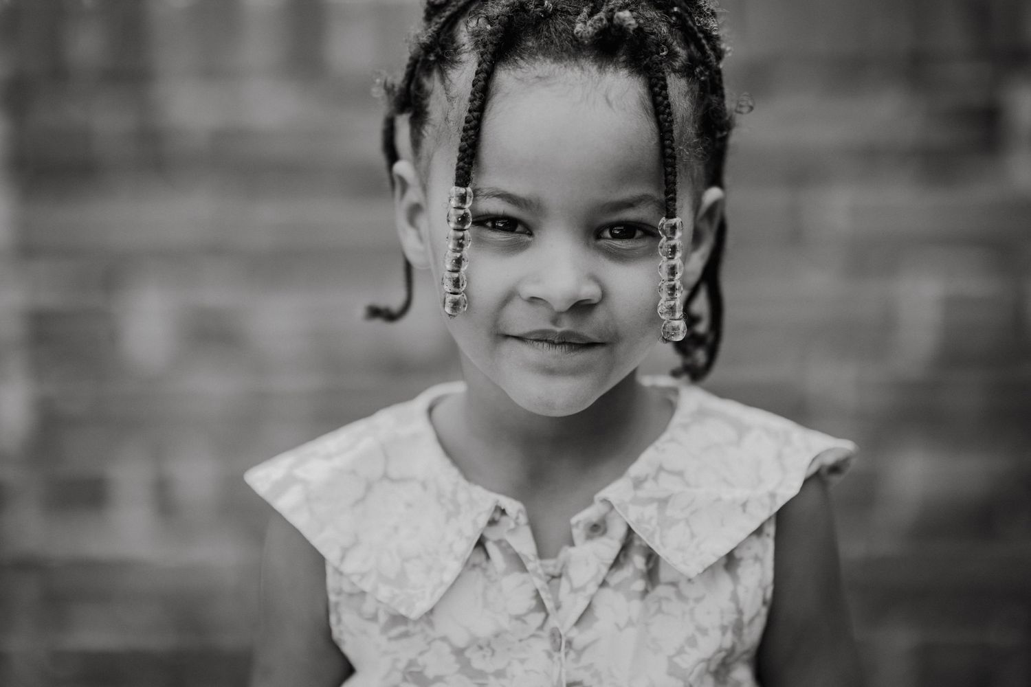 Black and white portrait series showing playful expressions against a brick wall.