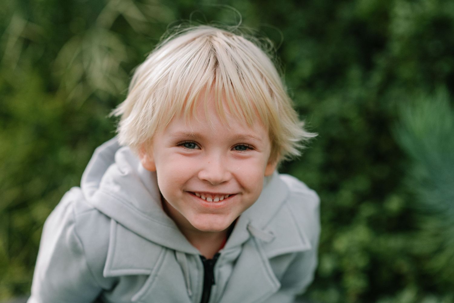 Candid outdoor portraits showing bright smiles against a natural green background.