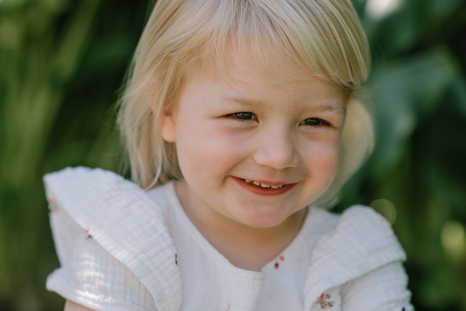 Sweet outdoor portrait with natural lighting and green foliage in background.