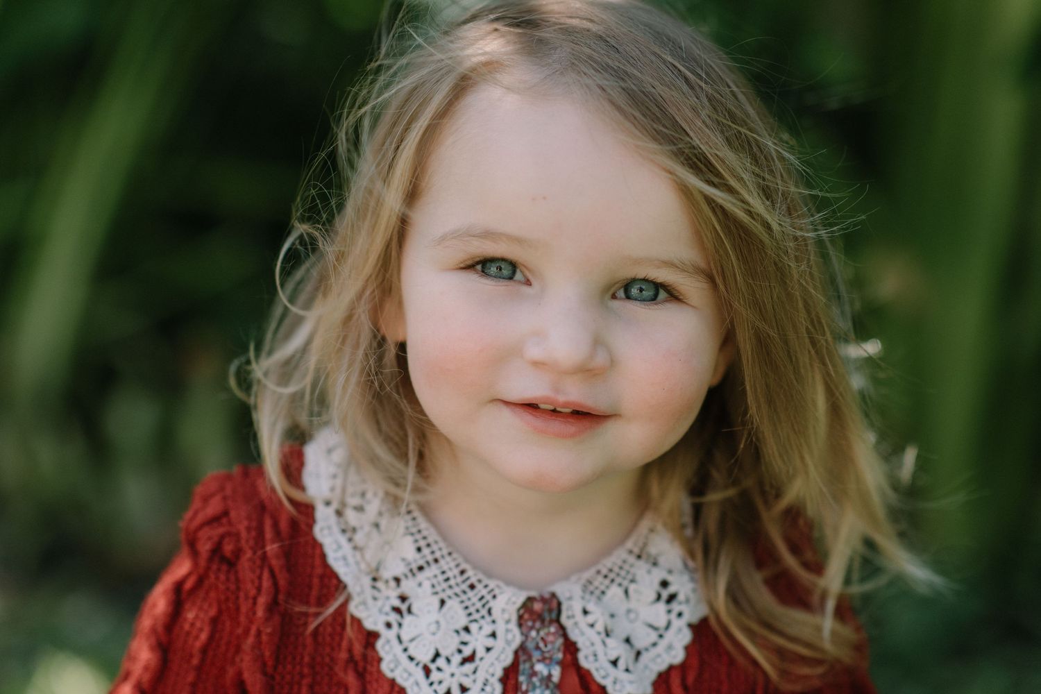 Portrait in a garden setting wearing a classic red dress with white collar.
