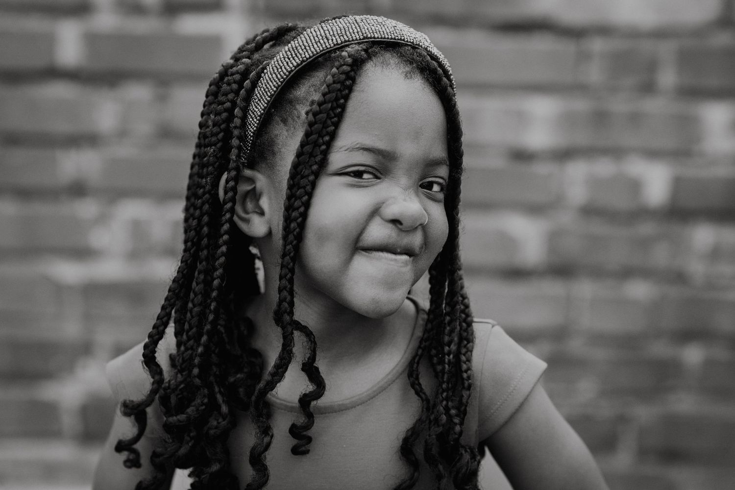 Series of portraits with braided hairstyles and bright smiles against brick backdrop.