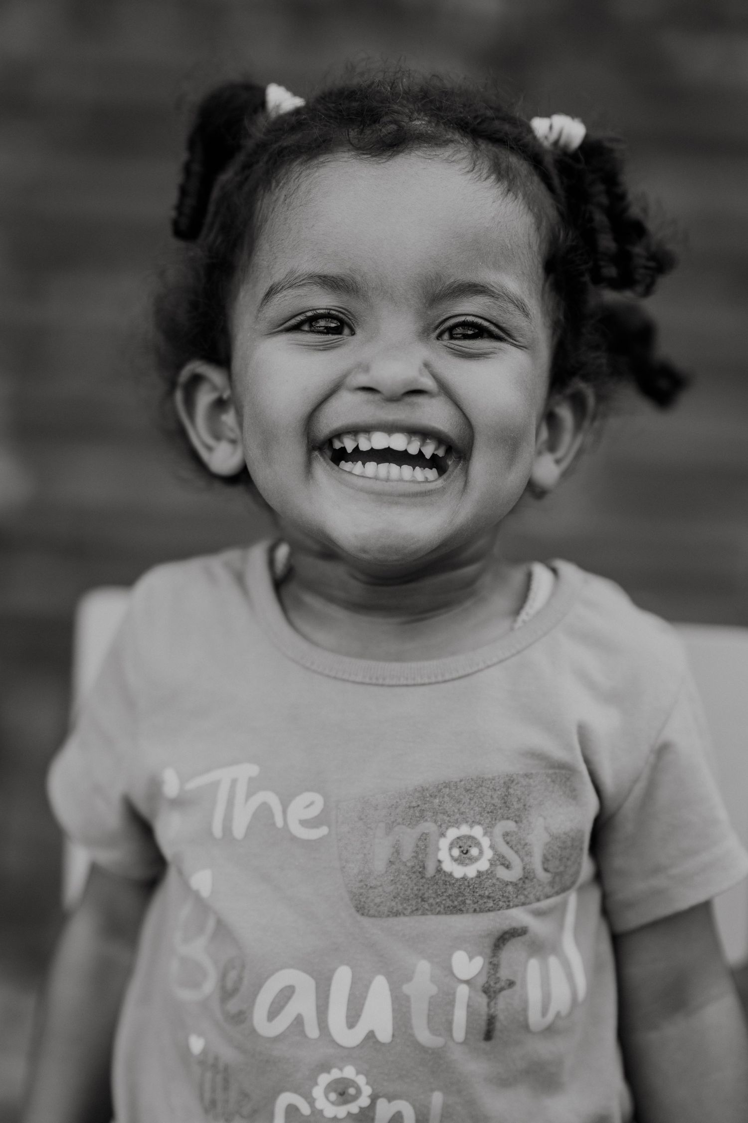 Black and white portraits showing joyful expressions and smiles against a brick wall.