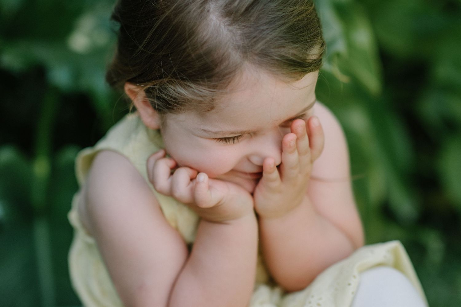 Candid moment of a child covering their face while playing outside.